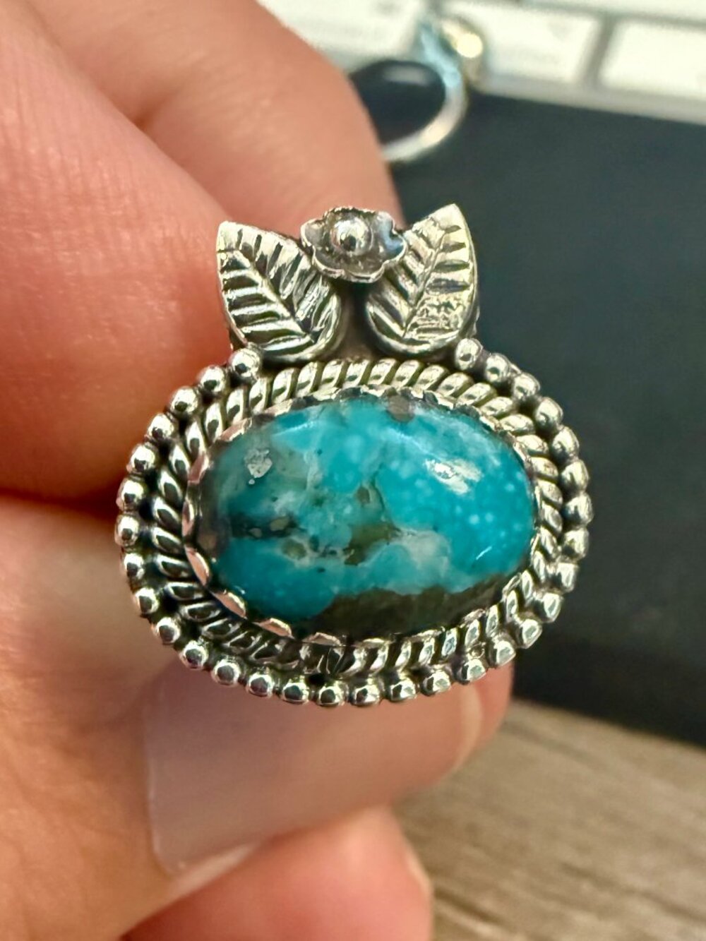 925 Kingman turquoise stone set against intricate leaf and floral ring